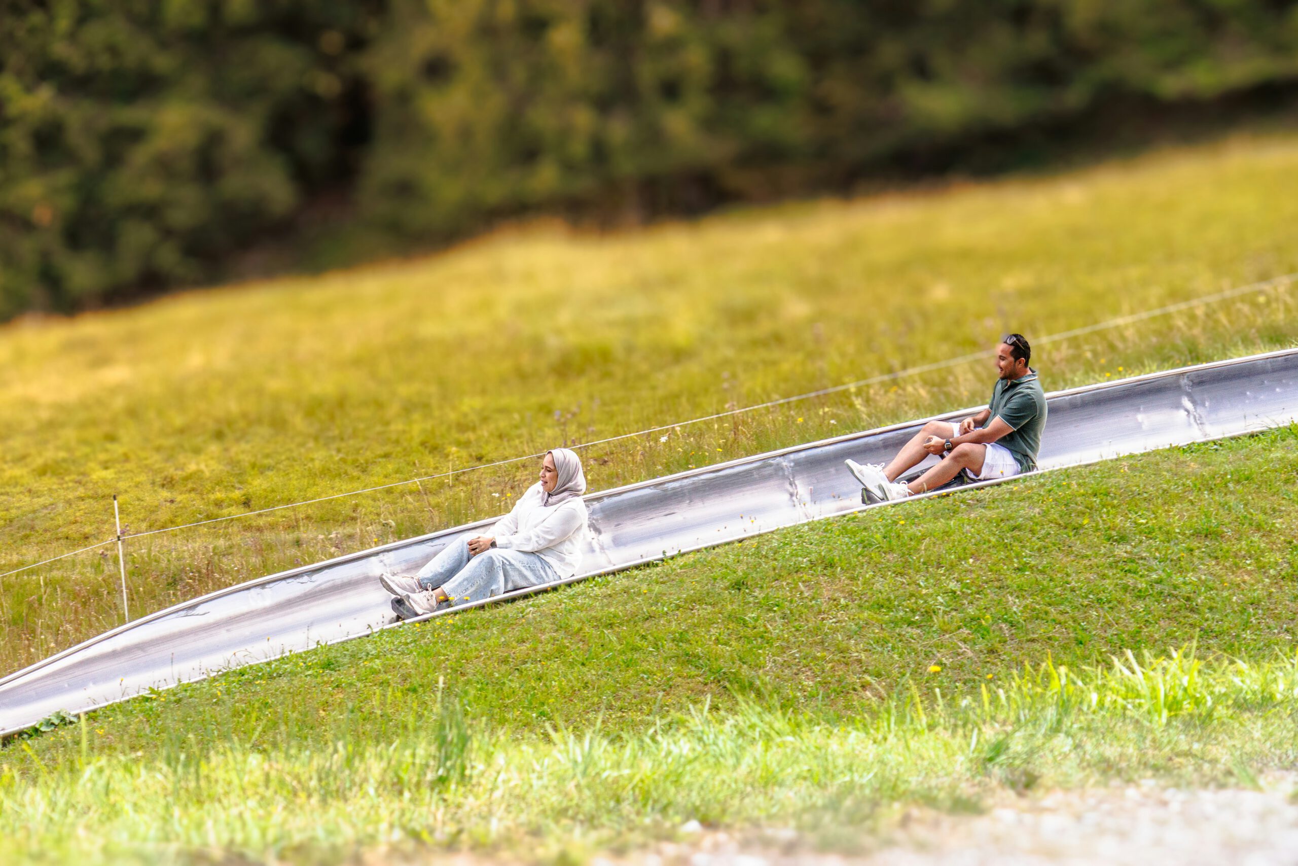 Zwei Personen auf einer Sommerrodelbahn-Schlittenstrecke im Grünen {{brizy_dc_image_alt imageSrc=